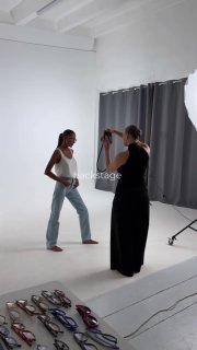 Студийная фотосъёмка новой коллекции оправ: модель в белой майке у фотографа на белом фоне; несколько оправ лежат на полу.