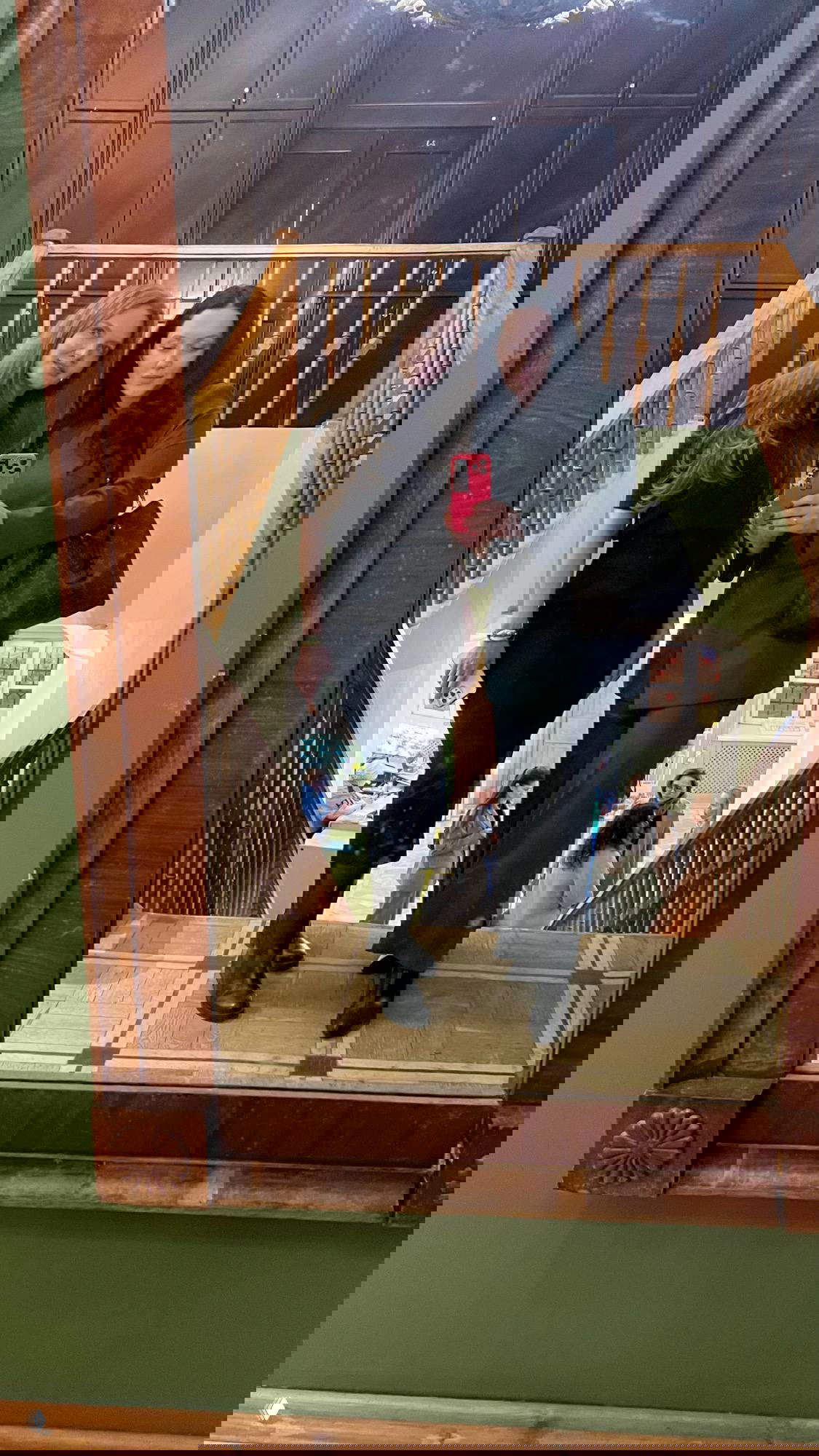 Зеркальное селфи двух участниц в холле конференции на лестнице, в отражении видно движение гостей и атмосферу вечера.