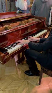 Руки человека, играющего на рояле в зале — музыкальный фрагмент вечера, передающий живую атмосферу дебатов и обсуждений.