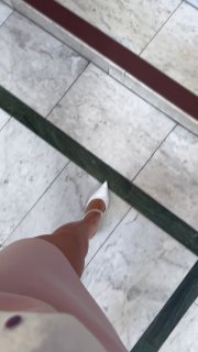 Кадр ног посетителя и пола музея: часть прогулочного ракурса в зале, фотография снизу вверх с акцентом на обувь и мраморный пол.