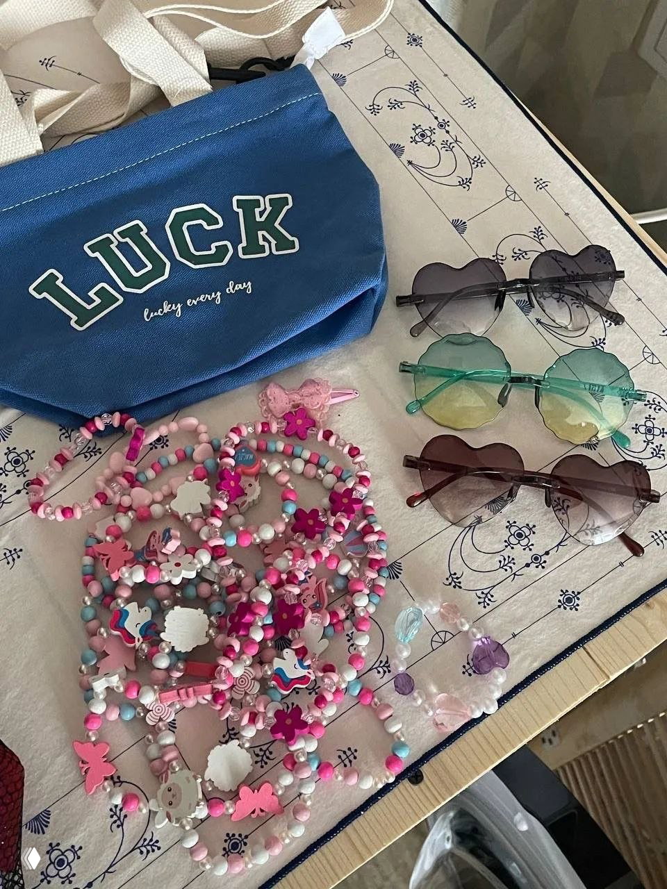 Сумка с надписью LUCK, несколько солнечных очков в форме сердца и детские бусы/браслеты — аксессуары и бижутерия для продажи.