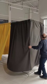 Сотрудник внутри устанавливает тёмный занавес на каркас торговой точки; видны элементы подготовки площадки перед КультТоргом.