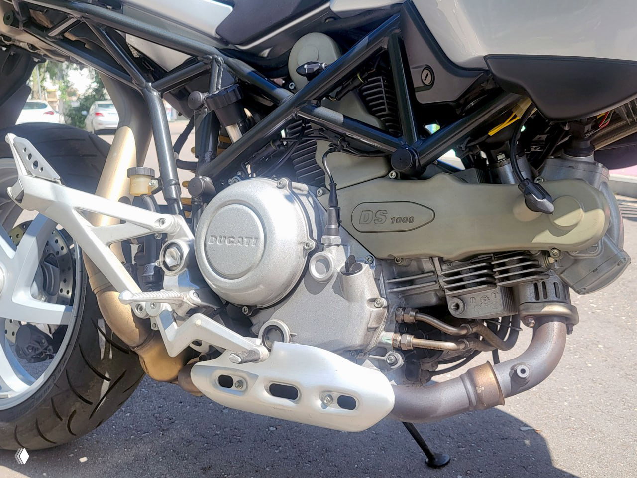 Крупный план двигателя и картера Ducati Multistrada DS1000: видны мотор, рама и коллекционная табличка, хорошее состояние узла на солнце. Фото для объявления и оценки состояния.