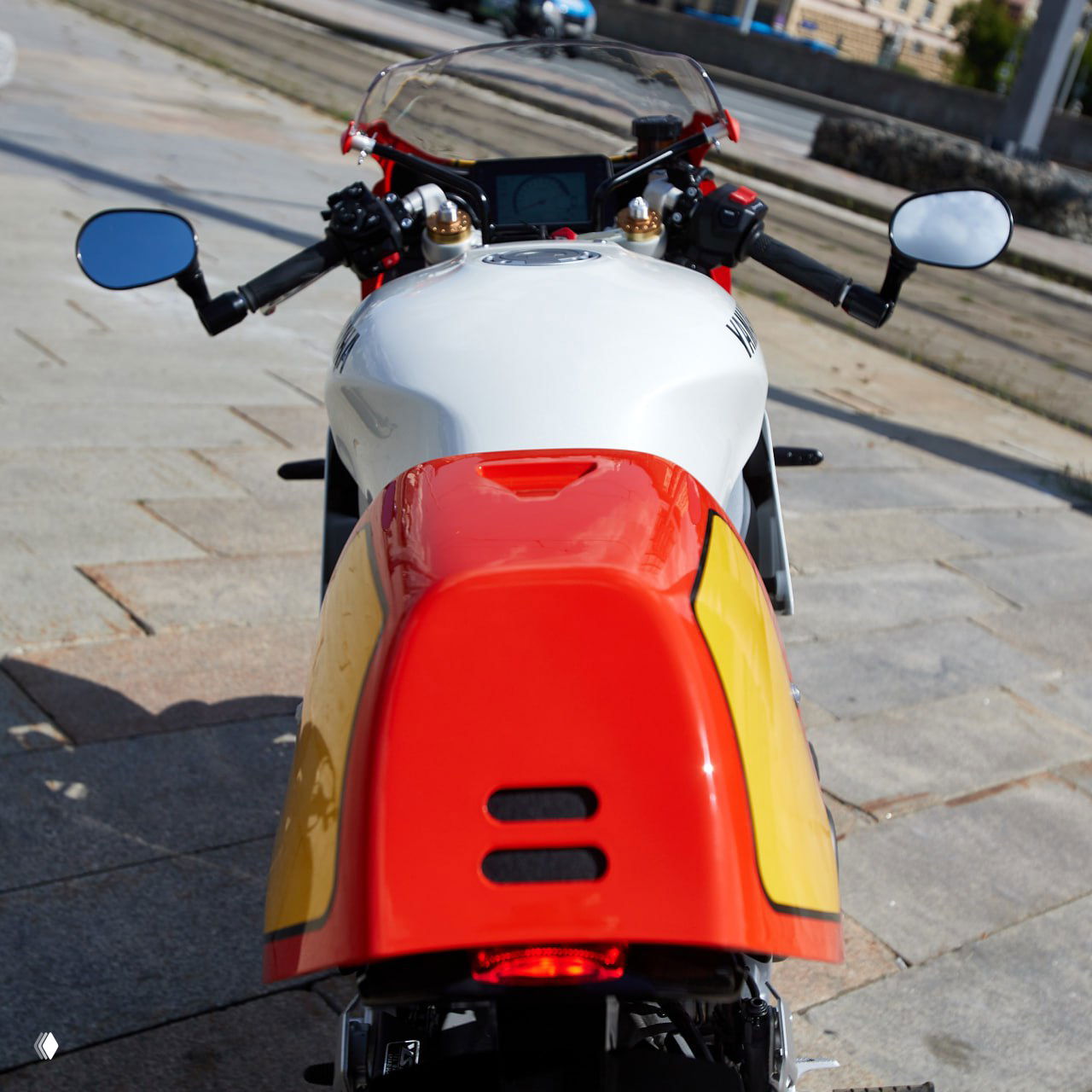 Вид сверху на бензобак и приборку Yamaha XSR900 GP: белый бак, небольшой ветровой экран и «цветной телевизор» приборки в ретро‑общем образе.