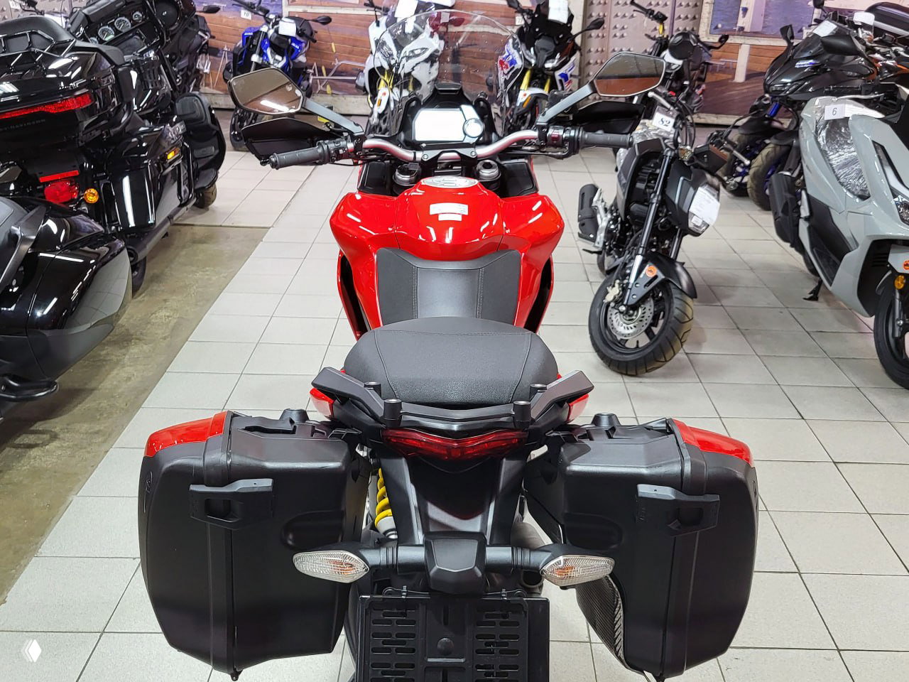 Вид сзади на Ducati Multistrada 1200 S: пара боковых кофров, сиденье и стоп-сигнал, магазинная обстановка на фоне.