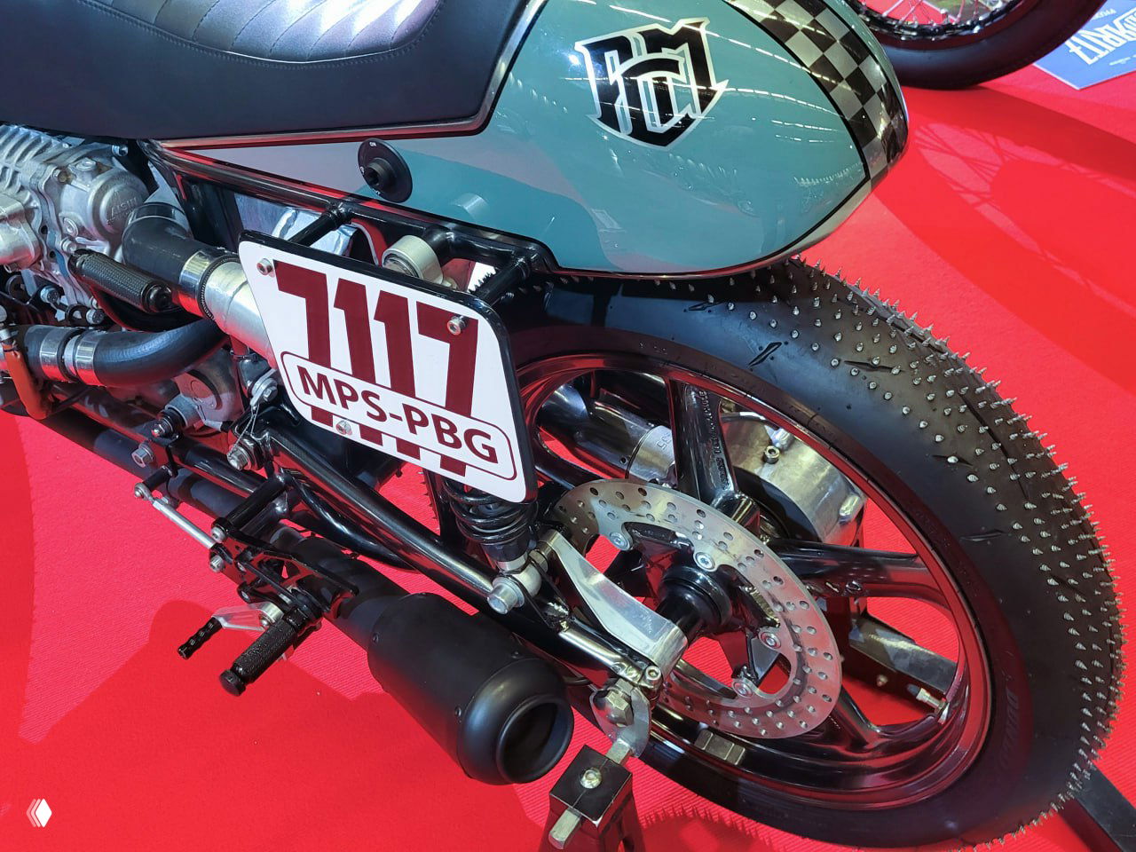 Яркий тюнингованный спортивный кастом с номером 12, цветной обтекатель и открытая задняя часть с видимыми компонентами трансмиссии на выставке.