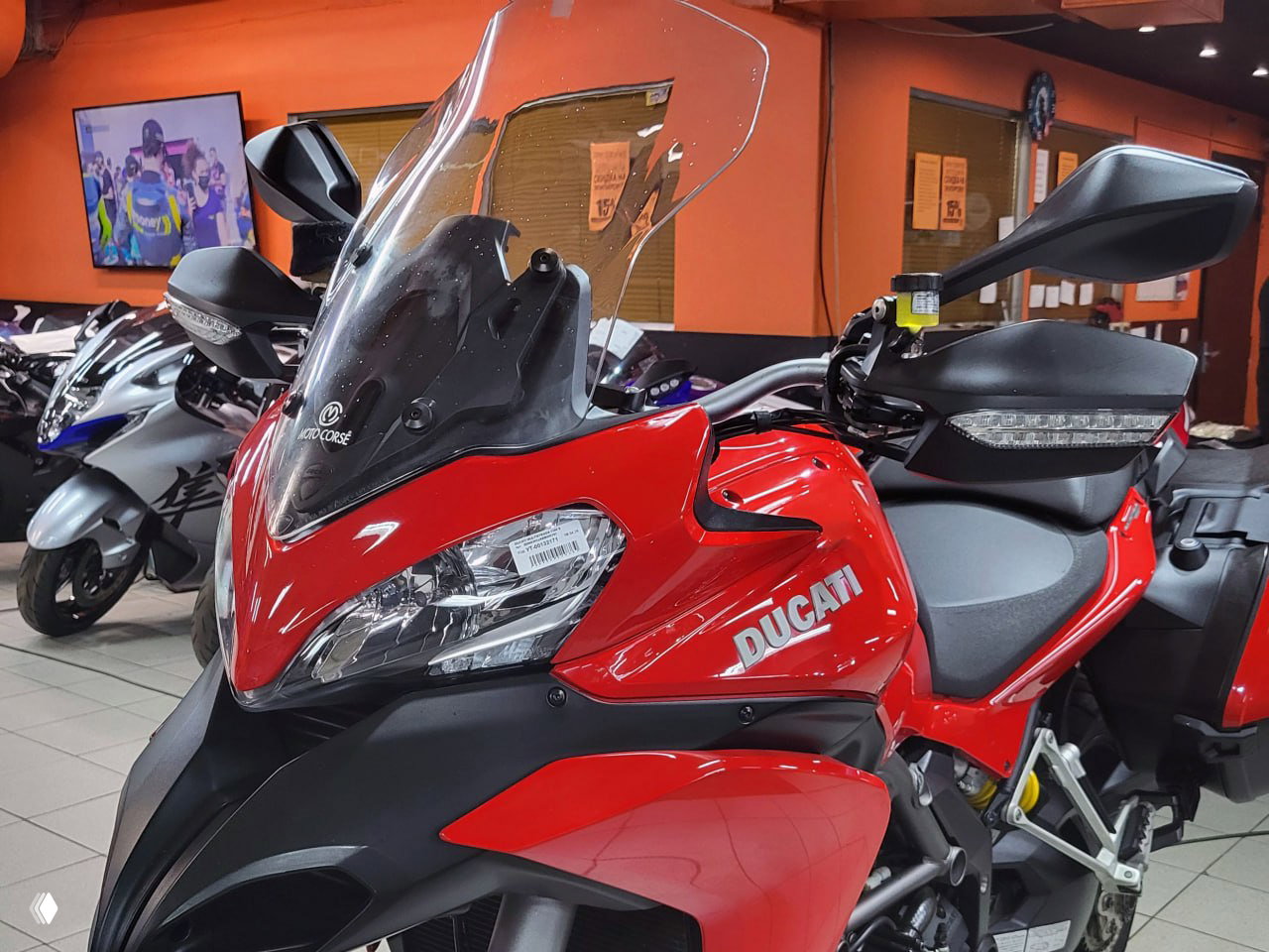 Крупный план переднего колеса Ducati Multistrada 1200 S: тормозной диск, суппорт Brembo и передняя вилка, видны дорожные покрышки.