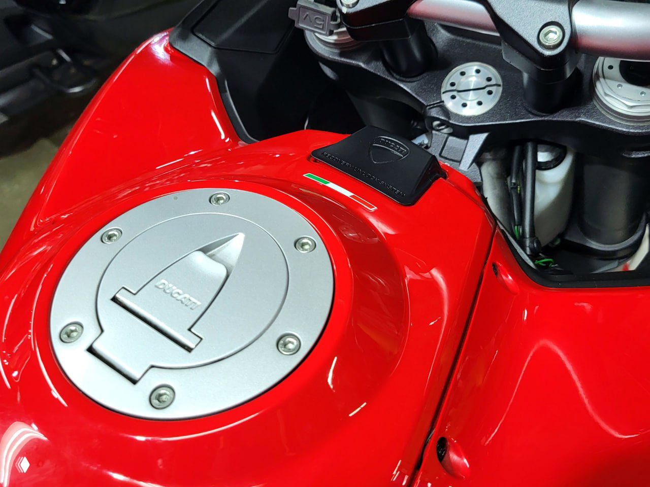 Крупный план топливного люка и консоли Ducati Multistrada 1200 S, красное лакокрасочное покрытие и детали управления видны детально.