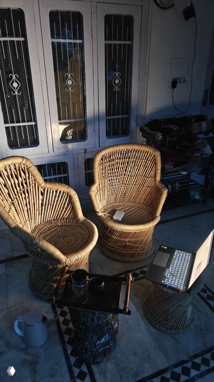 Уютный уголок с плетёными креслами, низким столом и открытым ноутбуком — рабочая зона в апартах с домашней атмосферой.