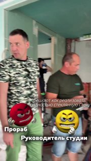 Двое мужчин на стройке обсуждают монтаж стеклянной перегородки у ванной; видны черновая отделка, проём для стены и инструменты.