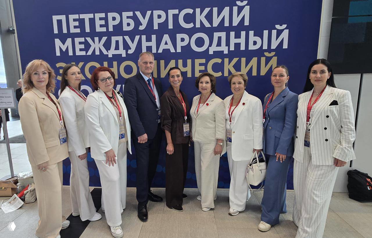 Групповая фотография делегатов у большого баннера «Петербургский международный экономический форум» — деловая атмосфера и официальные пропуска на фоне.