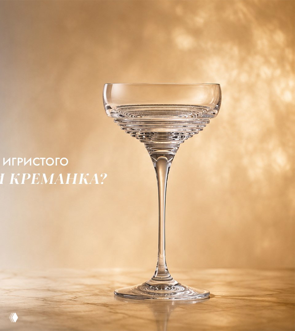 Широкая прозрачная креманка на тёплом золотистом фоне; показана широкая чаша и тонкая ножка, подчёркивающие ретро‑эстетику подачи игристого.