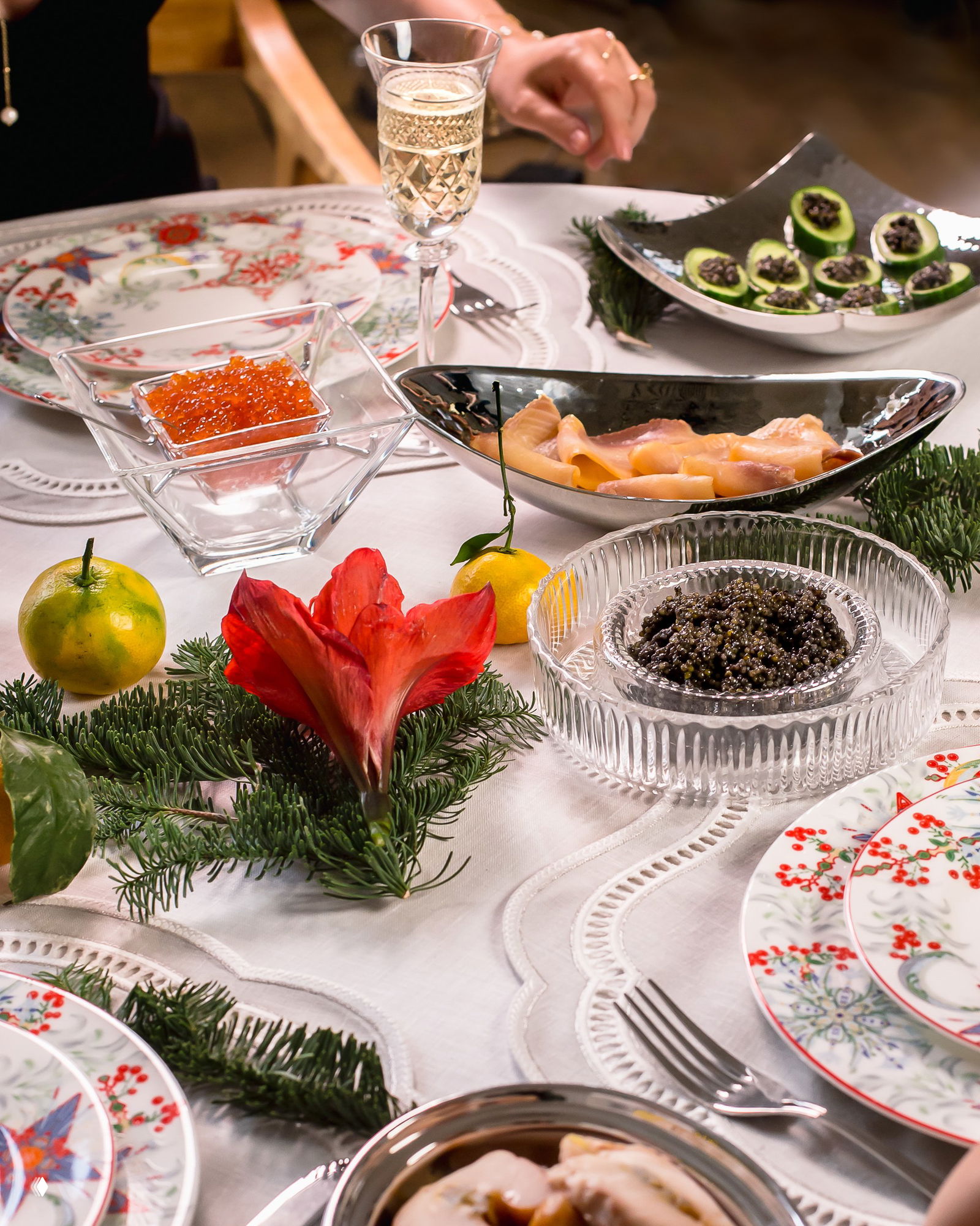 Праздничный сервированный стол с тарелками, бокалами, красной и черной икрой и декоративными элементами — общий план композиции.