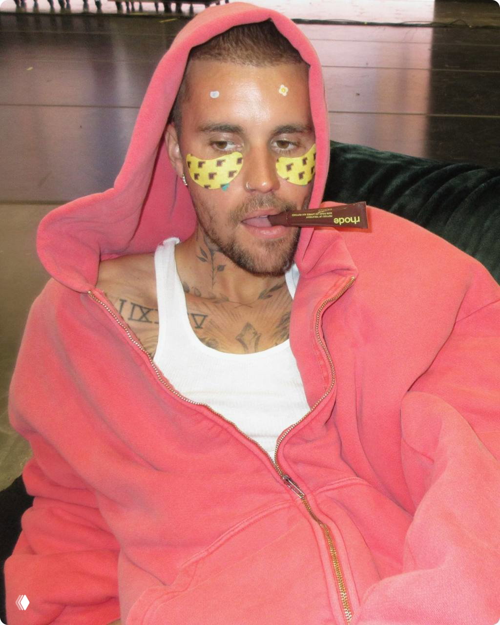 Промо‑кадр: мужчина в розовом худи с гидрогелевыми патчами под глазами держит тюбик тритмента, атмосферный бэкстейдж‑снимок рекламной кампании.