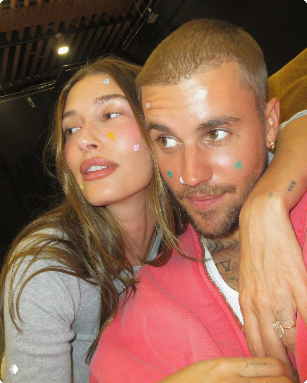 Дуэт на съёмке: двое людей крупным планом, на лицах разноцветные декоративные точечные наклейки и патчи — стилизованный рекламный снимок коллекции.