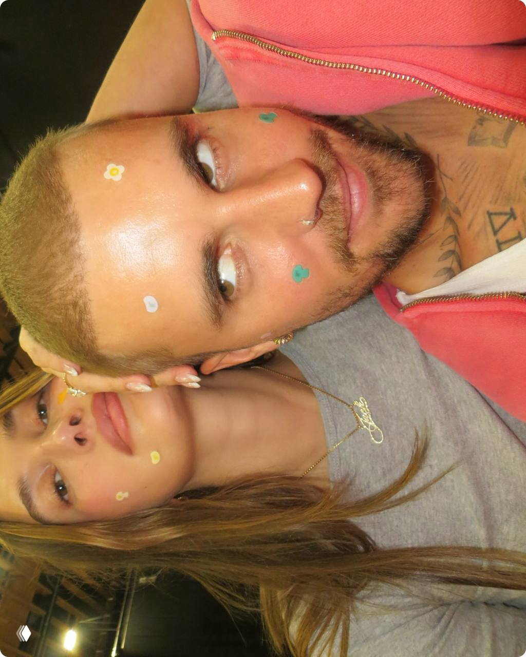 Крупный портретный кадр в нестандартной ориентации: пара вблизи, на лицах декоративные наклейки и патчи, ощущение закулисья и естественности съемки.