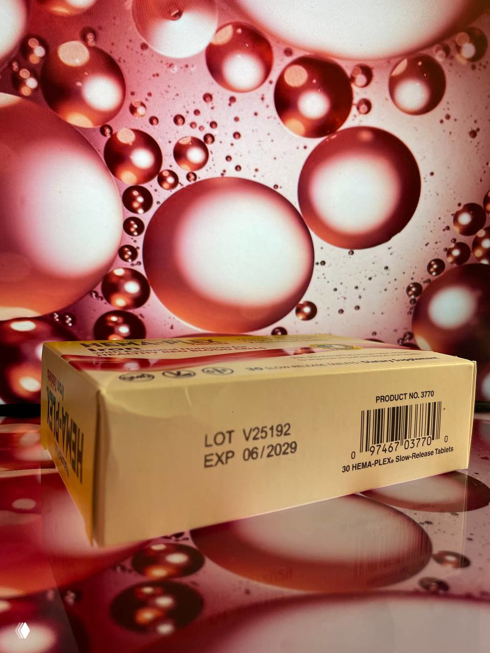 Изображение дна коробки HEMA-PLEX с маркировкой LOT V25192 и сроком годности EXP 06/2029 на том же декоративном розовом фоне.