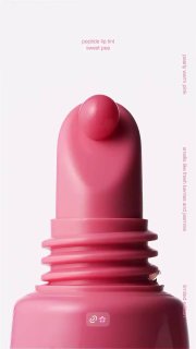 Крупный план аппликатора тинта rhode с каплей продукта на носике и пастельным фоном; видно форму аппликатора и кремовую консистенцию средства