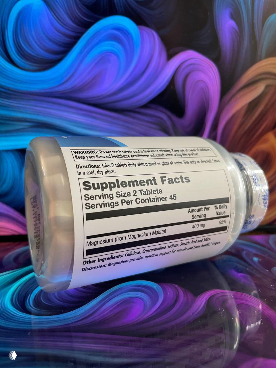 Этикетка с блоком Supplement Facts и указанием Serving Size 2 Tablets на лежащей банке KAL Magnesium Malate 400; видно состав и дозировку.