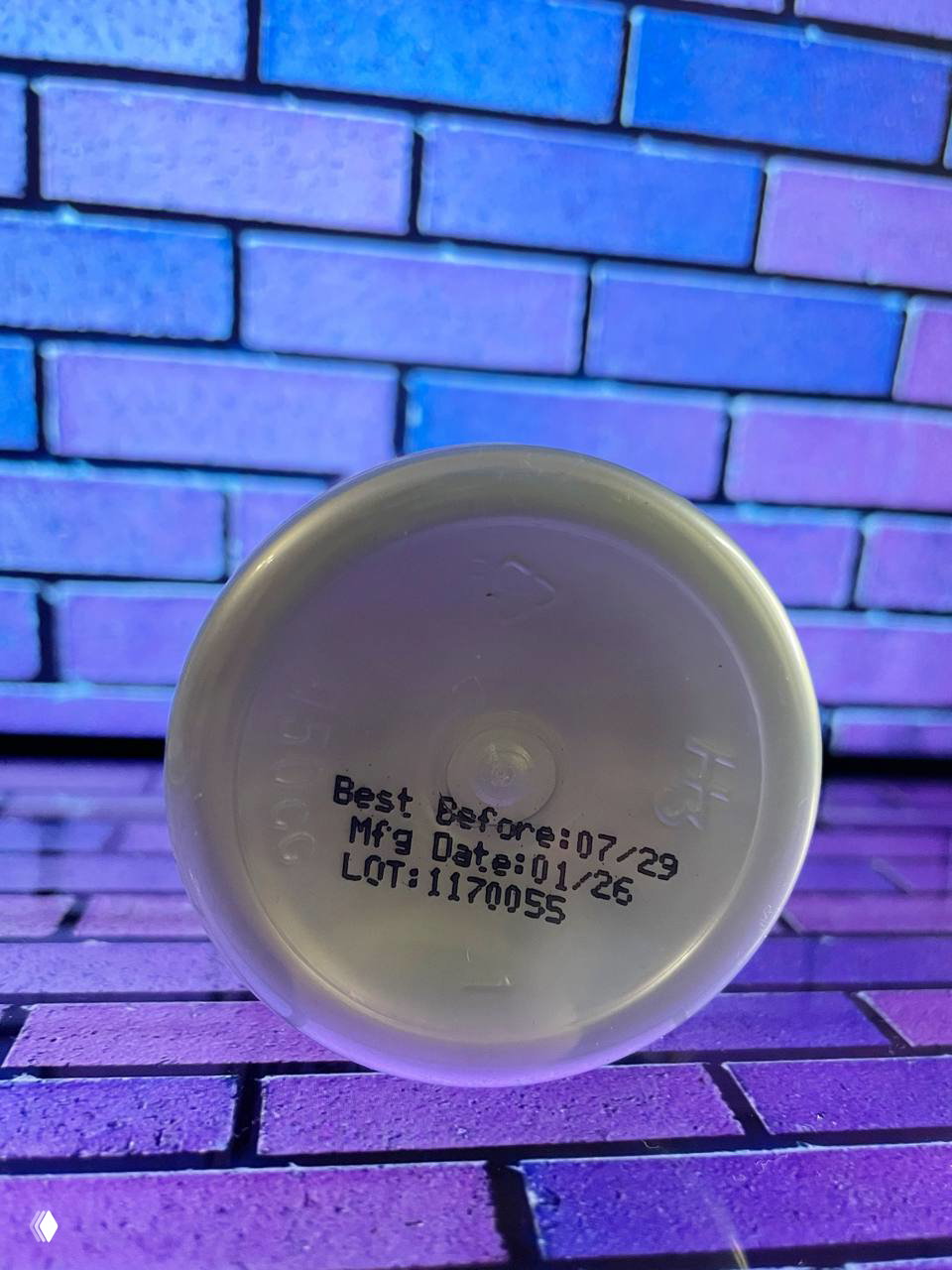 Дно упаковки KAL с отпечатанной датой Best Before 07/29, Mfg Date 01/26 и LOT:117005S на фоне того же яркого кирпичного фона.