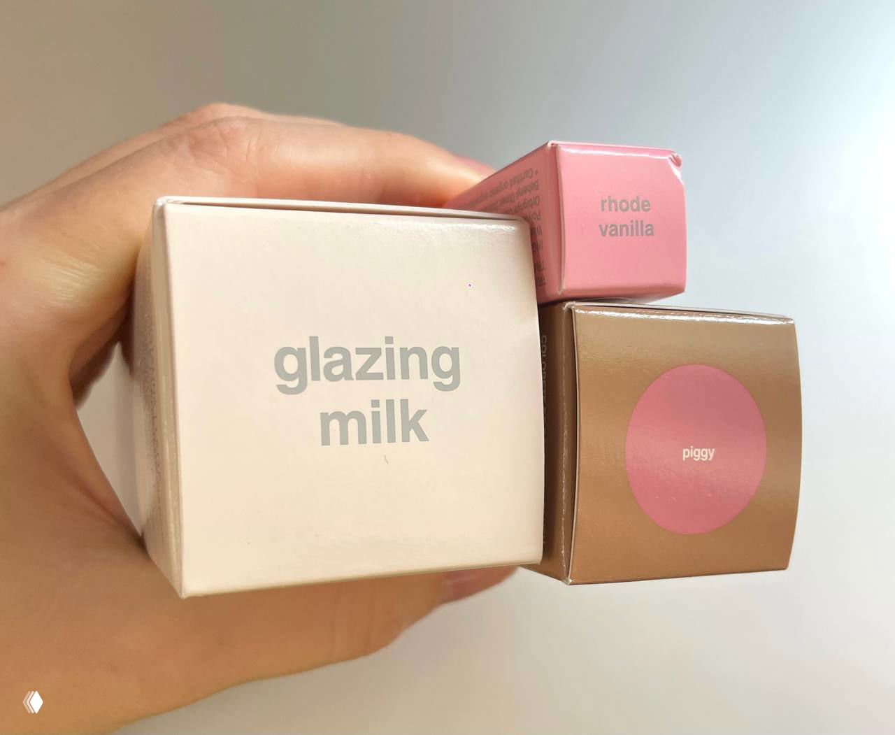 Крупный план трёх коробочек с надписями «glazing milk», «rhode vanilla» и «piggy» — видно брендовую упаковку и маркировку оттенков.