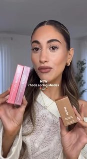 Женщина держит коробочки и тюбики Rhode у лица, макияж в естественных тонах, демонстрация оттенков румян и блесков