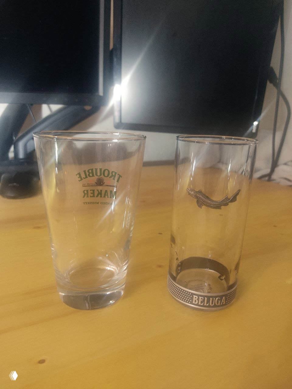 Два высоких стакана на столе: один универсальный хайбол, второй цилиндрический шот/стопка с эмблемой Beluga — сравнение объёмов и формы.