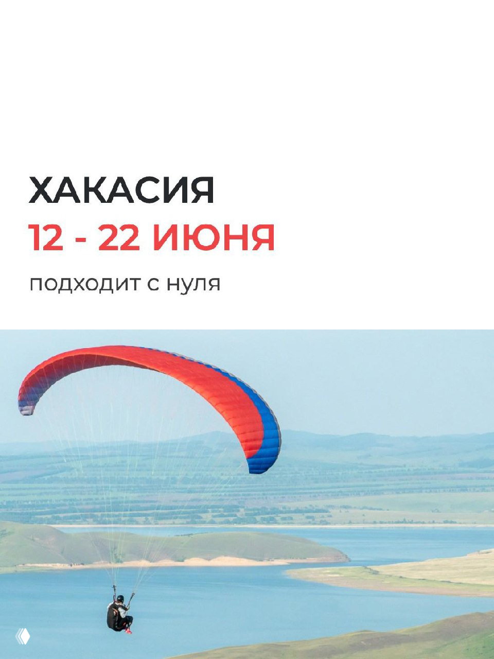 Парапланист в воздухе над озером и равниной: красно-синий купол, вид на береговую линию и открытый ландшафт Хакасии в ясную погоду.