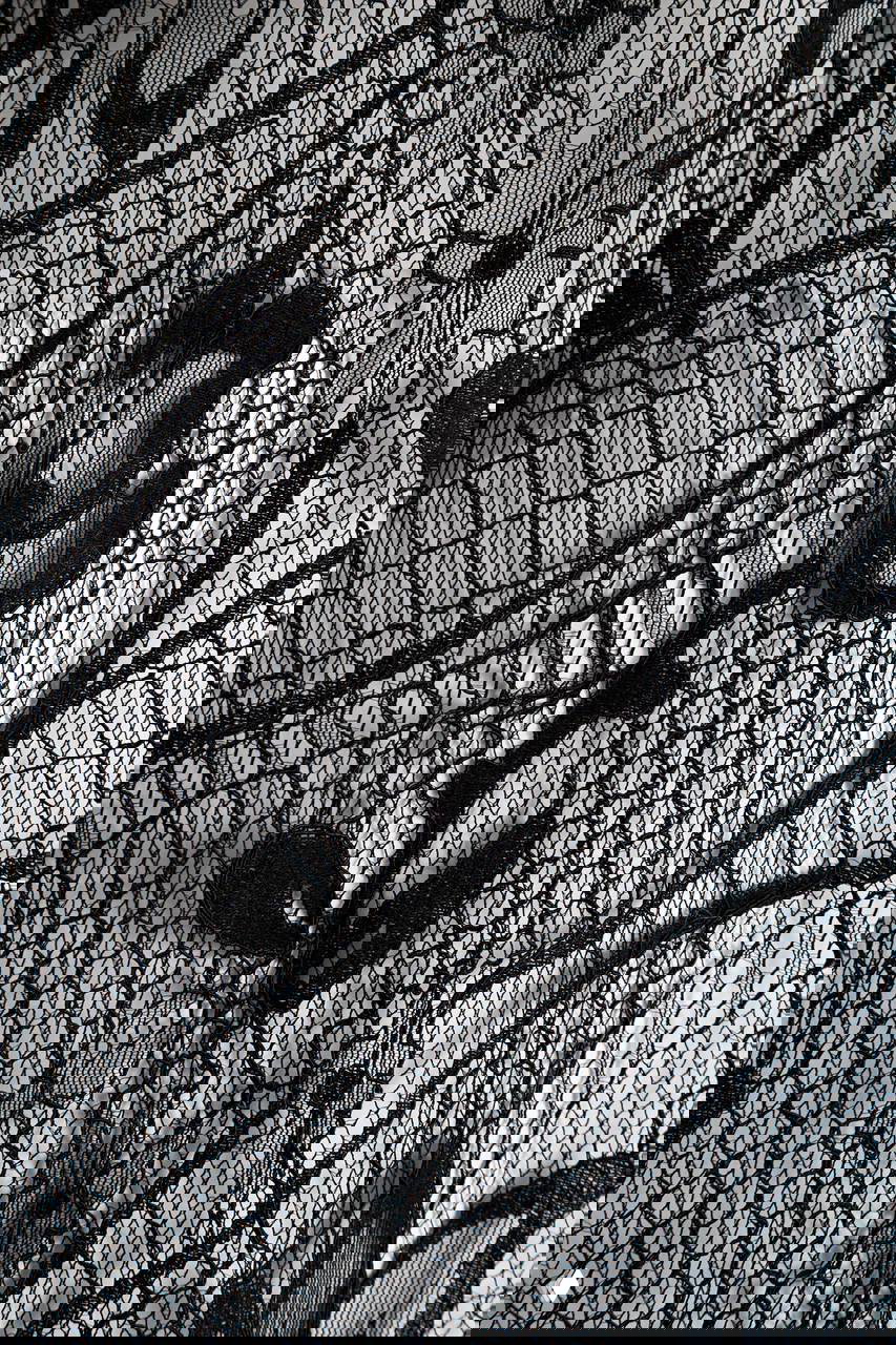 Крупный план чёрного кружева с растительным орнаментом: тонкая сетка, вышитые мотивы и текстура ткани крупным планом.