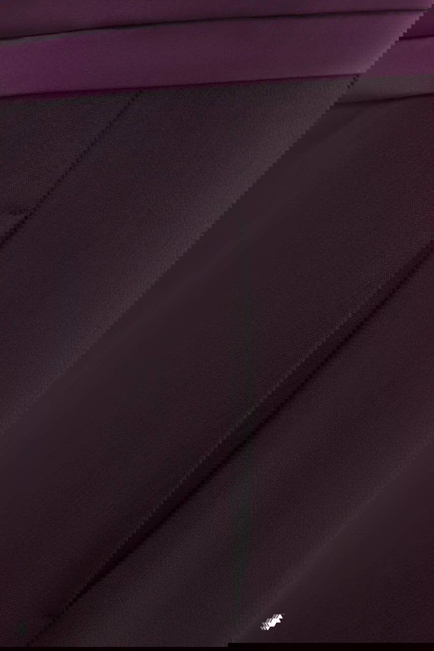 Крупный план бордовой ткани и бокового шва изделия: структура материала, аккуратная строчка и тонкая отделка кромки.