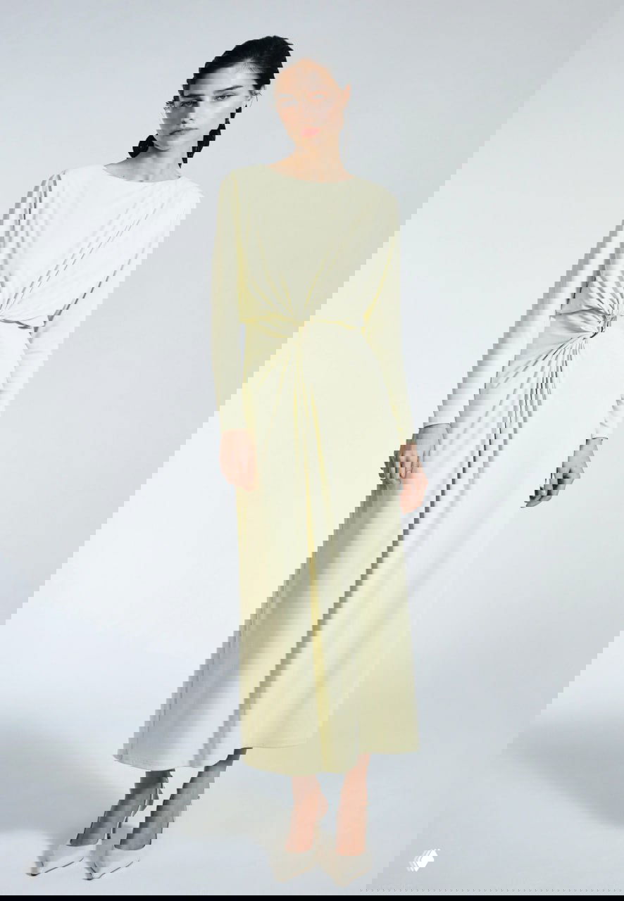 Модель в светлом длинном платье с драпировкой и длинными рукавами, элегантный офисно-праздничный образ на нейтральном фоне.