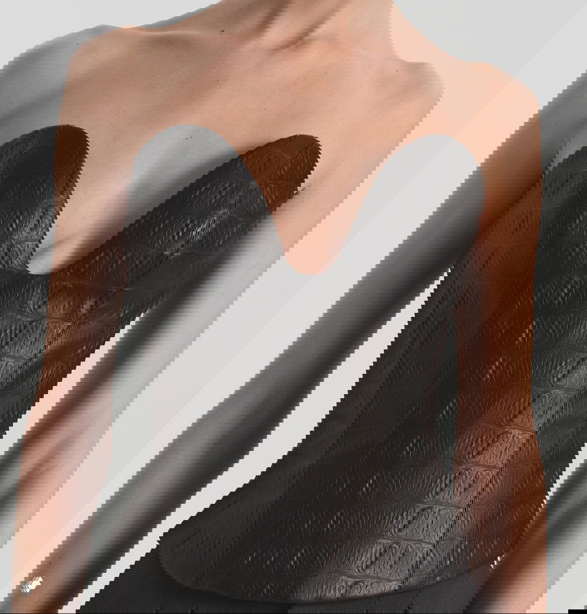 Черный корсет с тиснением под кожу и глубоким сердцевидным вырезом на торсе модели; подчёркнутая структура и посадка.