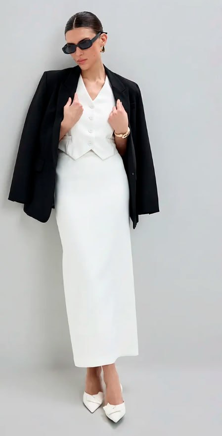 Женский образ в длинной белой юбке и чёрном пиджаке с жилетом; строгий офисный стиль с контрастными аксессуарами и солнечными очками.