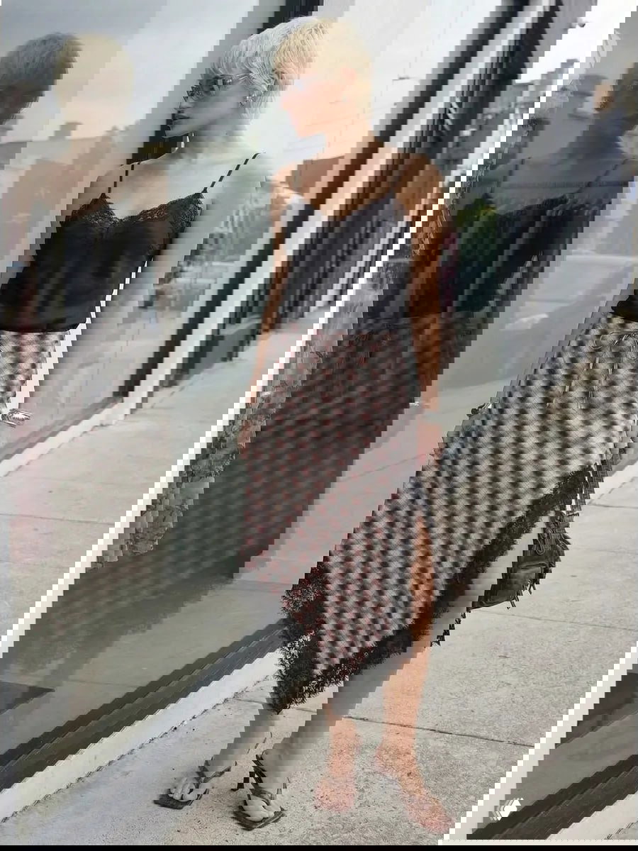 Ассиметричная клетчатая юбка с кружевной отделкой на городской улице; сочетание фактур и небрежный уличный стиль в кадре.