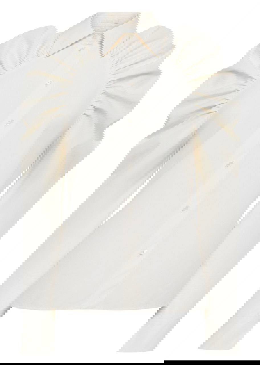 Кремовая рубашка с пышными рукавами на белом фоне, крупный план изделия: воротник, сборки на плечах и аккуратные застёжки.