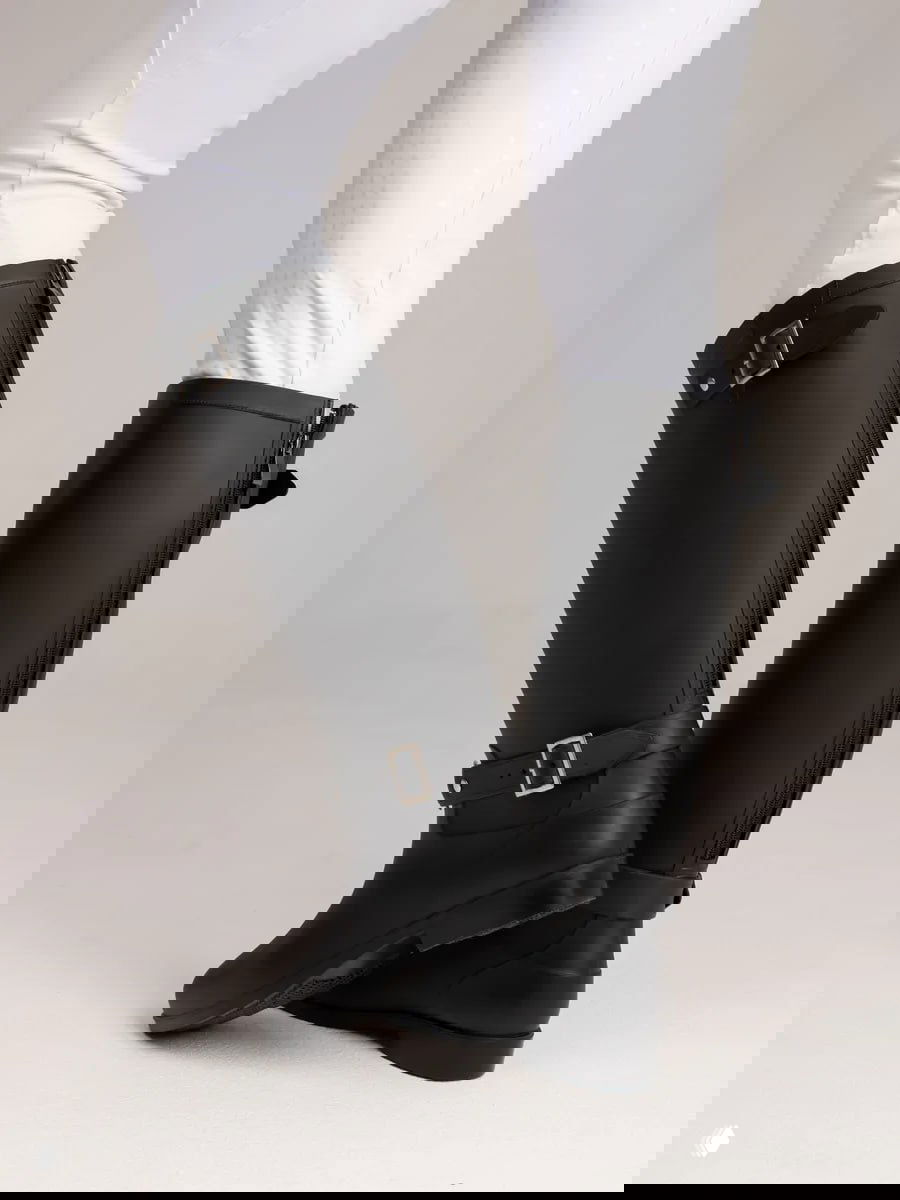 Высокие чёрные резиновые сапоги до колена на модели в белых легинсах, классический вариант для дождя.