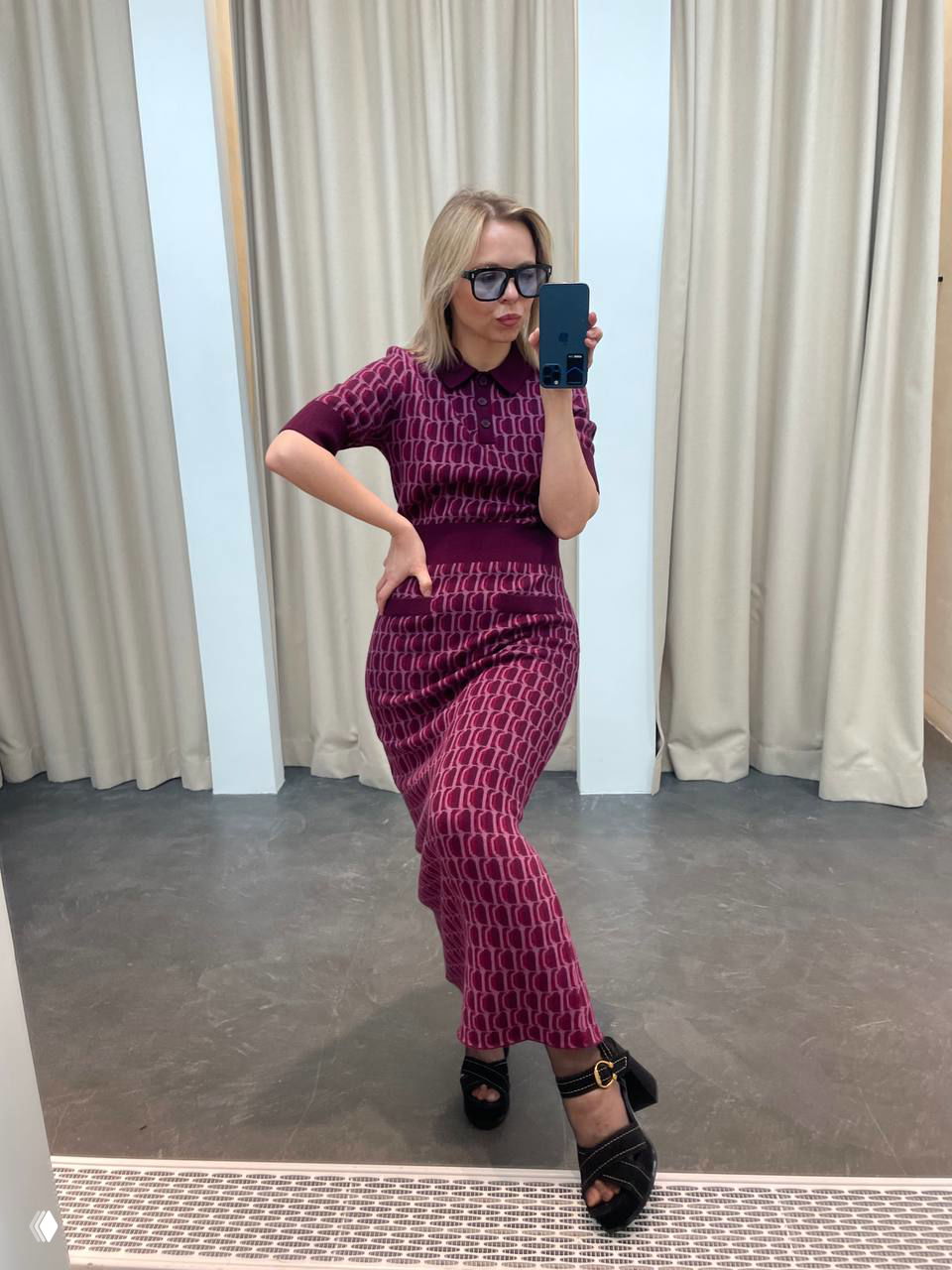 Полный рост в зеркале: комплект платье‑трикотаж с геометрическим узором бордового оттенка и босоножки на каблуке, поза у примерочной.