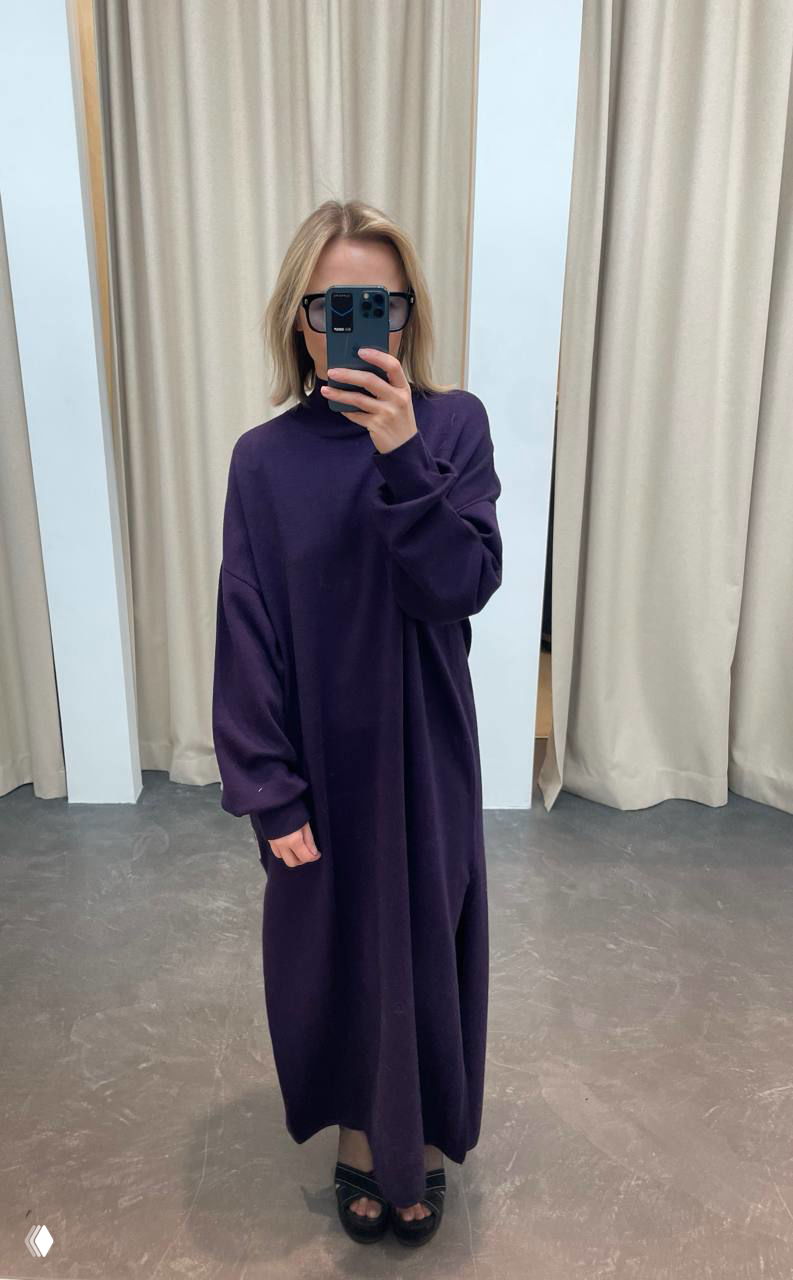 Зеркальное селфи в полный рост: длинное тёплое тёмно‑фиолетовое платье без пояса, видна обувь и шторы примерочной в магазине.