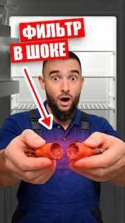 Мастер в синей форме держит два осушительных патрона на фоне открытого холодильника; крупный план и надпись «ФИЛЬТР В ШОКЕ».