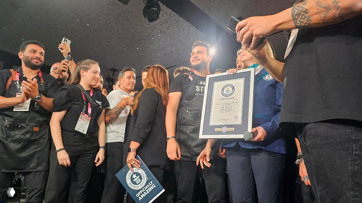 Сцена награждения: команда барберов на сцене держит плакетку Книги рекордов Гиннеса, вокруг организаторы и публика.