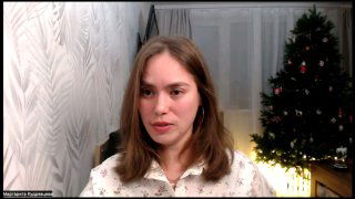 Женщина в домашней студии перед веб‑камерой, на заднем плане украшенная ёлка и интерьер — кадр подкаста об общении в семье и праздниках.