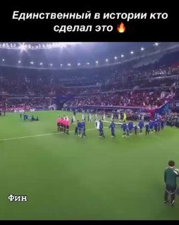 Футбольный стадион: игроки и судьи на поле перед началом, видны трибуны и освещение — кадр из ролика о сейвах Матвея Сафонова.