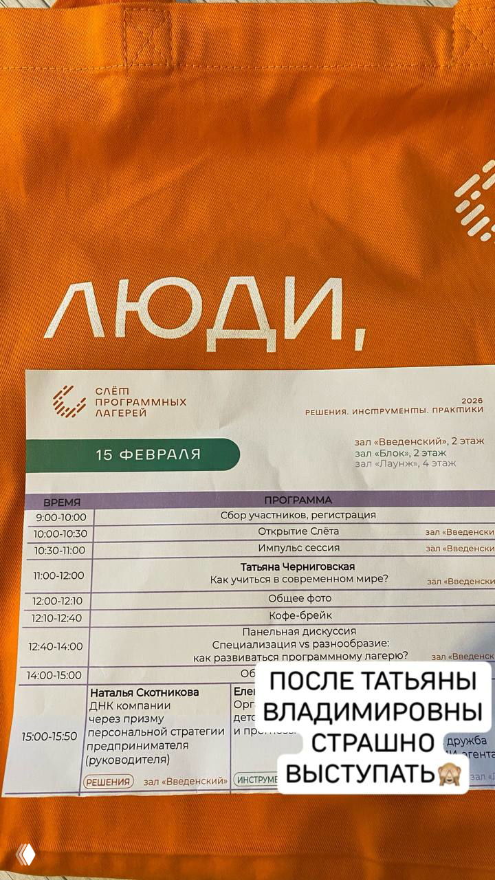 Оранжевая сумка мероприятия с программой Слета программных лагерей: расписание с указанием лекций и секций, крупный план бумажного буклета.