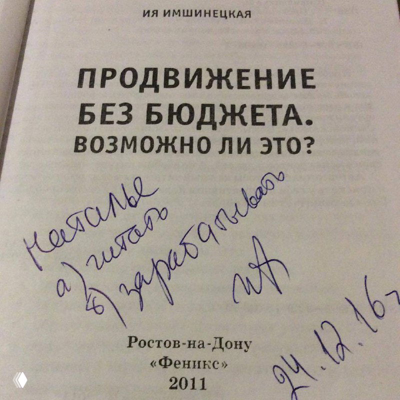 Фотография в зале: Наталья в светлом свитере с планшетом в руках, взгляд в камеру, рабочая атмосфера мероприятия и участники вокруг.