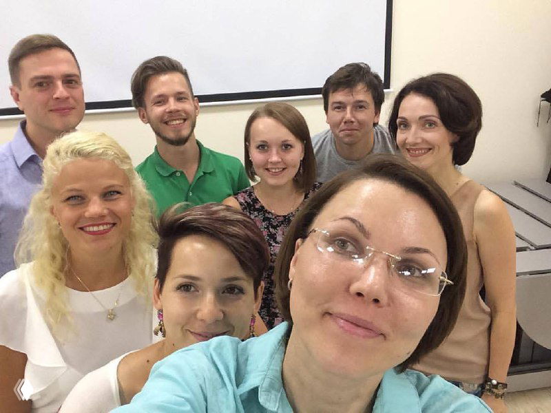 Групповое фото участников мероприятия, несколько улыбающихся людей, коллективная атмосфера, изображение искажено цифровыми артефактами.