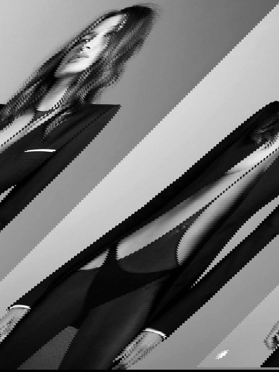 Чёрно‑белая портретная фотография Хейли Бибер в прозрачном боди и пиджаке с глубоким вырезом; акцент на линиях корпуса и вечернем образе.