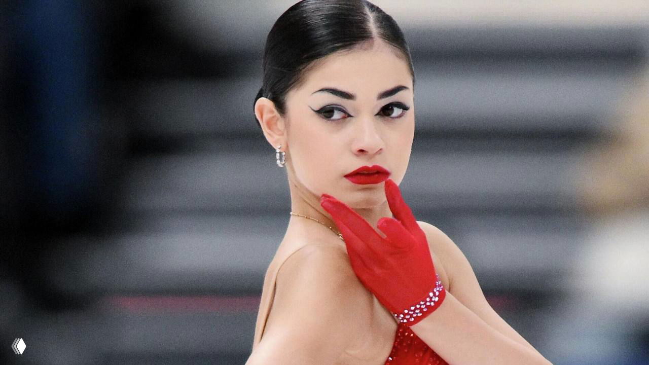 Портрет фигуристки Аделии Петросян в красном костюме и перчатке во время короткой программы на Олимпиаде‑2026.