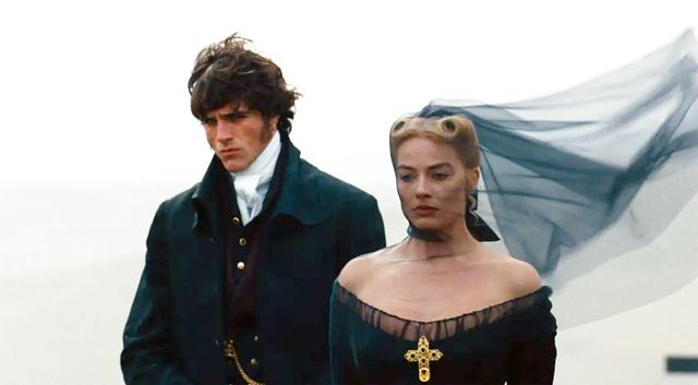 Два персонажа в костюмах эпохи стоят в кадре: у одного заметно открытое декольте на фоне развевающегося вуали, сценический момент.