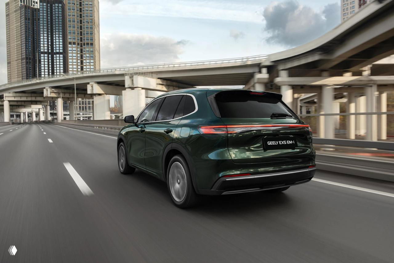 Geely EX5 EM-i в зелёном цвете едет по городской эстакаде, вид сзади и слегка в перспективе — подчёркнуты задние фонари и силуэт кузова.