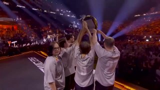 Игроки Team Spirit поднимают трофей на сцене финала EWC по Counter‑Strike: команда празднует, зрители и яркое сценическое освещение